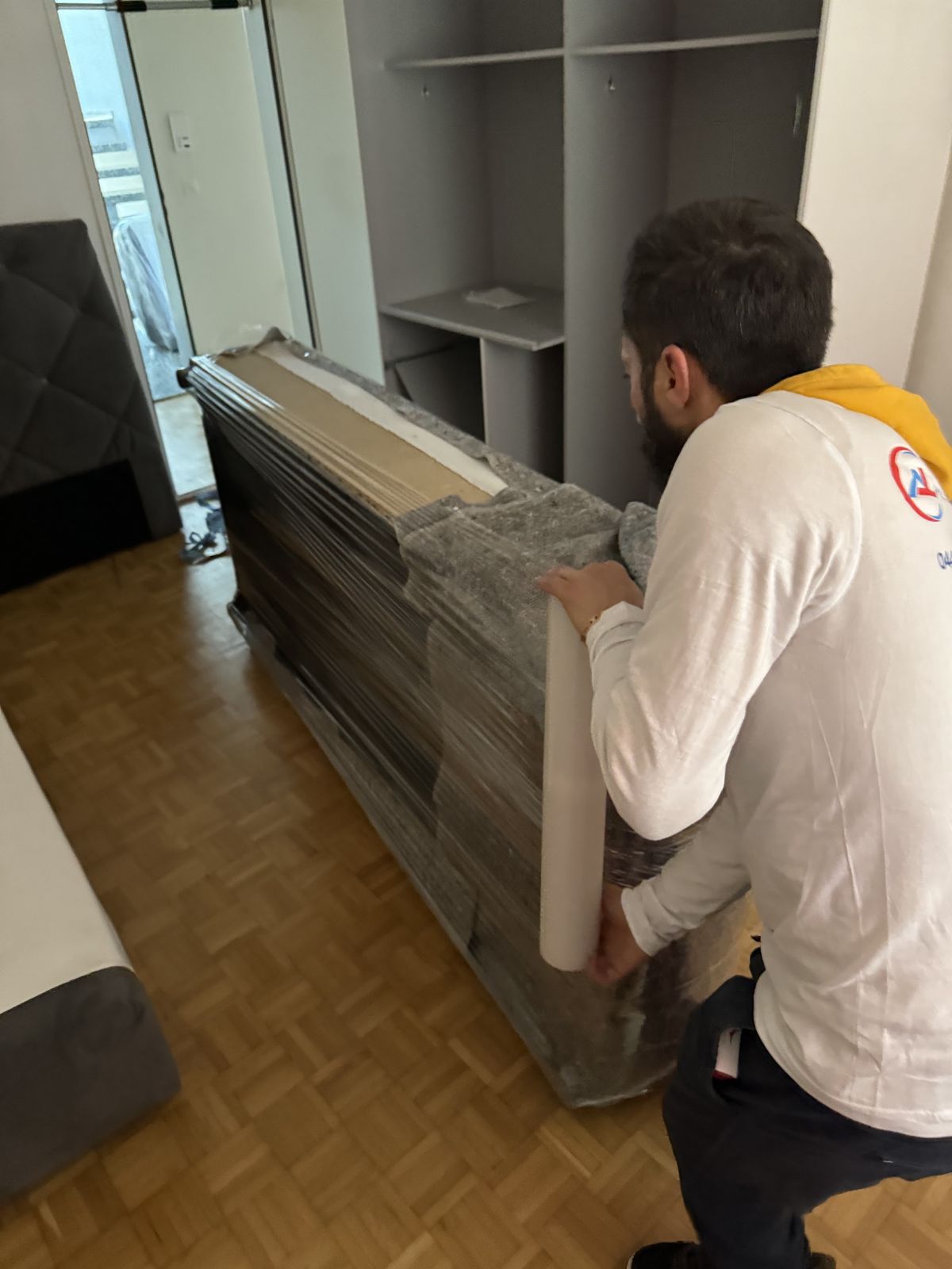 Mitarbeiter verpackt ein Möbelstück in Schutzfolie