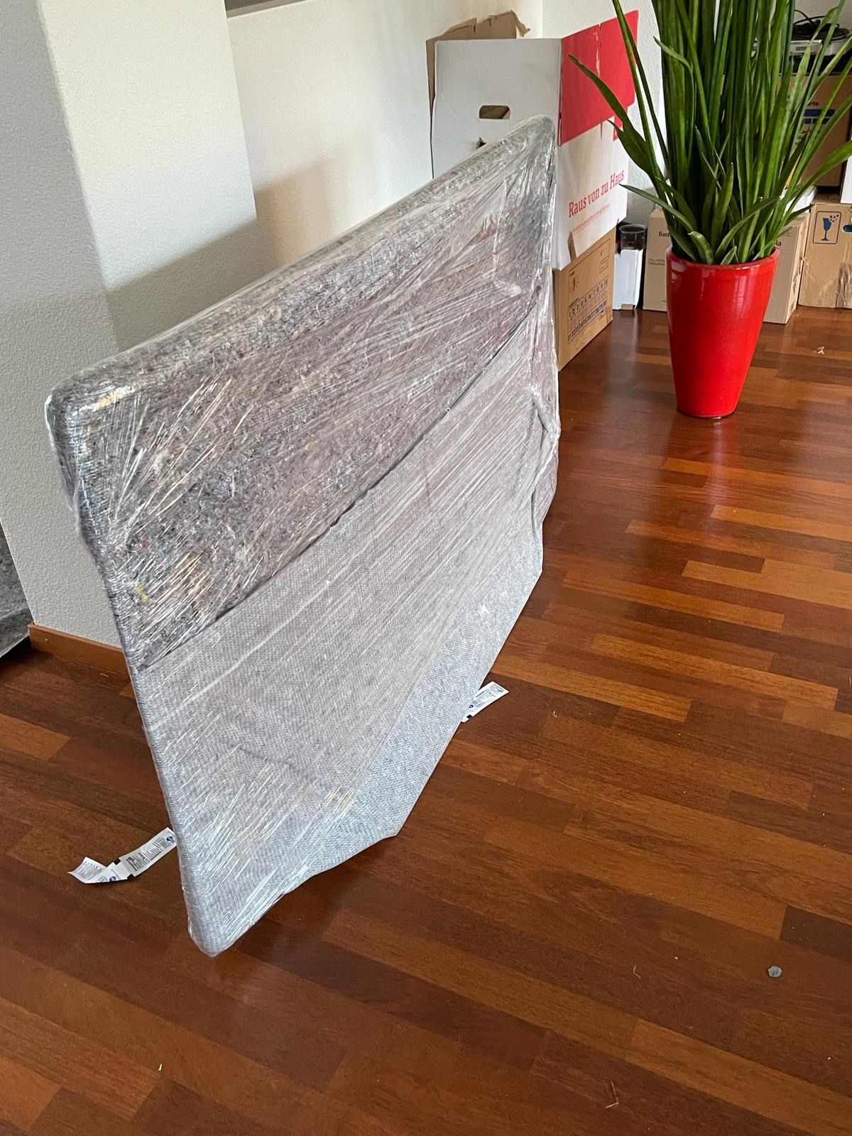 Möbelstück mit Schutzverpackung in einem Raum mit Parkett